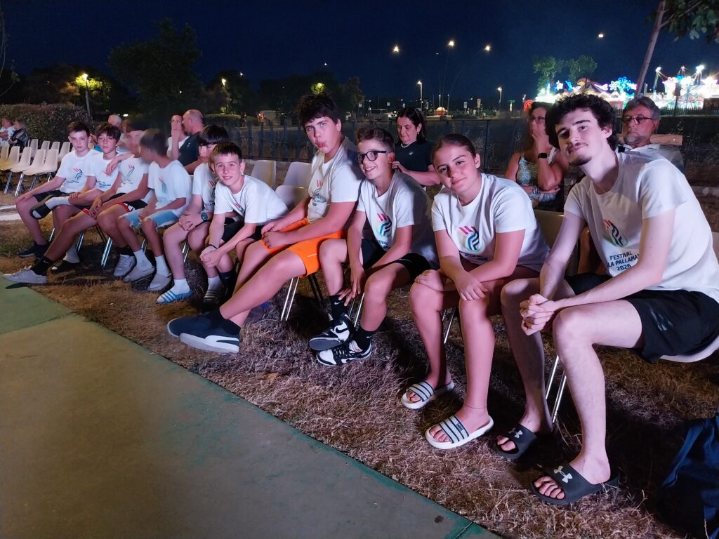 Ragazzi e accompagnatori alla serata del Festival, con le giostre illuminate sullo sfondo