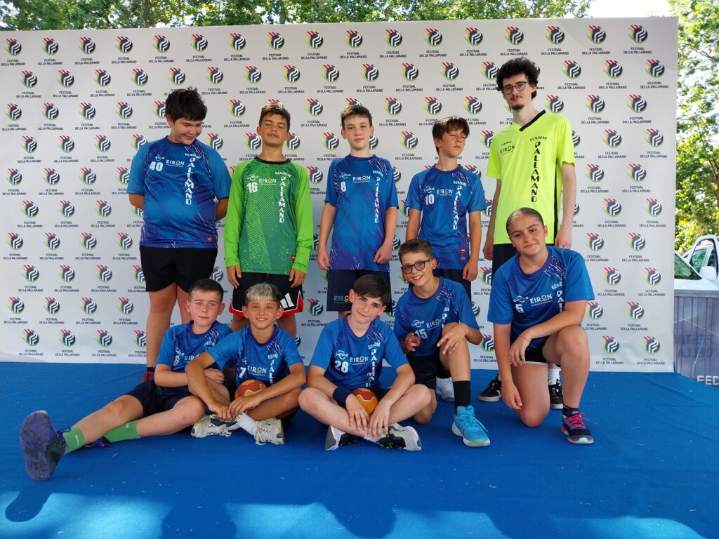 La squadra in divisa blu posa davanti al fondale del Festival della Pallamano