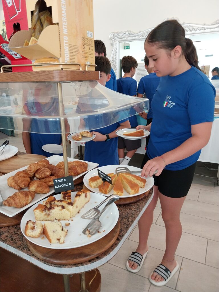 Giovane atleta si serve al banco dei dolci della colazione