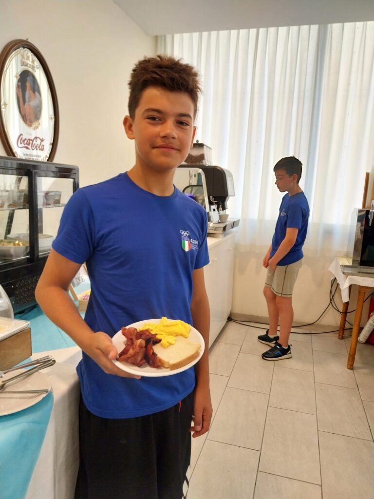 Giovane atleta del Bondone con il piatto della colazione in sala ristorante