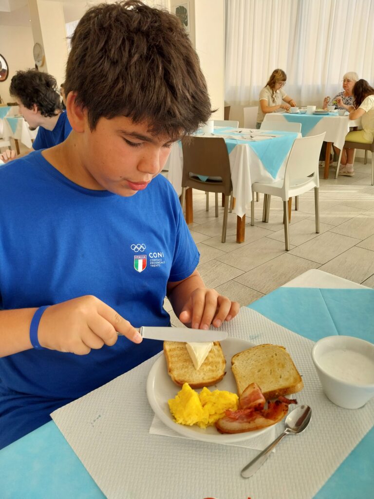 Giovane atleta fa colazione al tavolo della sala ristorante